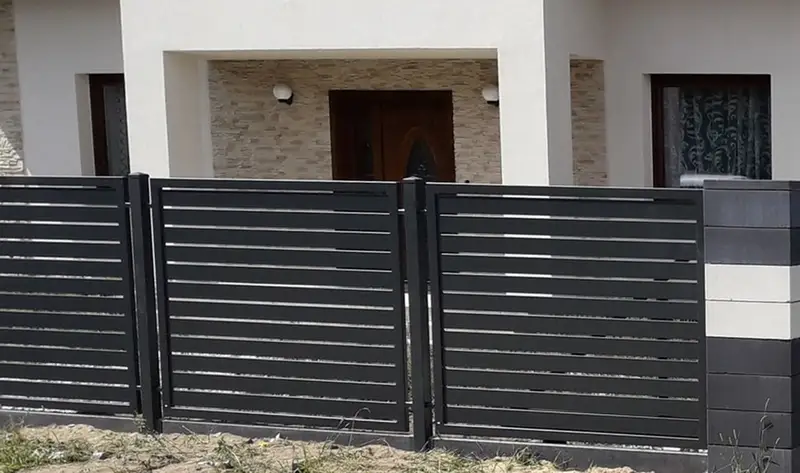 Ogrodzenie z grafitowych profili i czarnych słupków przed domem