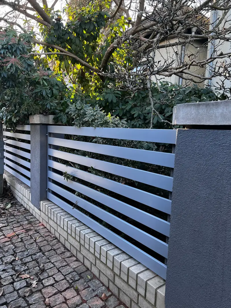 Szare ogrodzenie z poziomych profili na murku