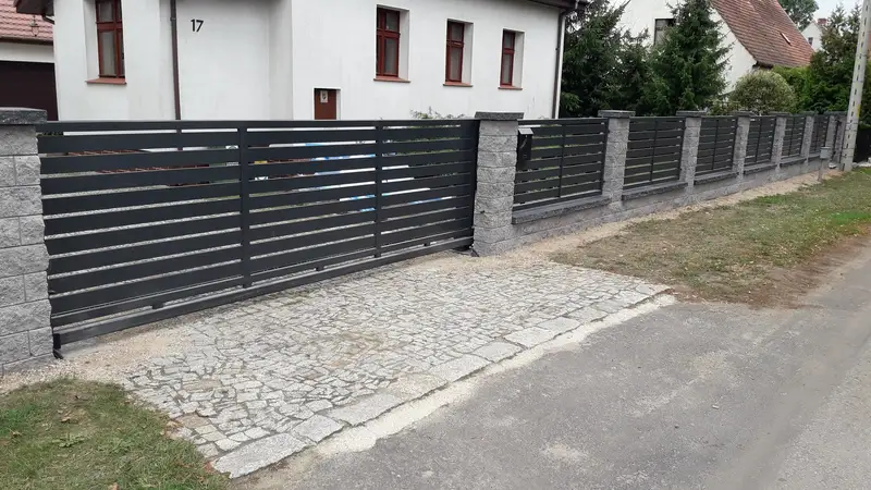 Długi odcinek ogrodzenia palisadowego wzdłuż chodnika